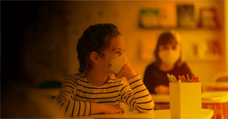 Foto zum Thema "Stau in der Umsetzung unseres modernen Bildungssystems?", wo ein Mädchen mit FFP2-Mundschutz im Klassenzimmer zeigt.